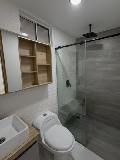 Baño remodelado con mueble de madera, revestimientos y ducha de vidrio